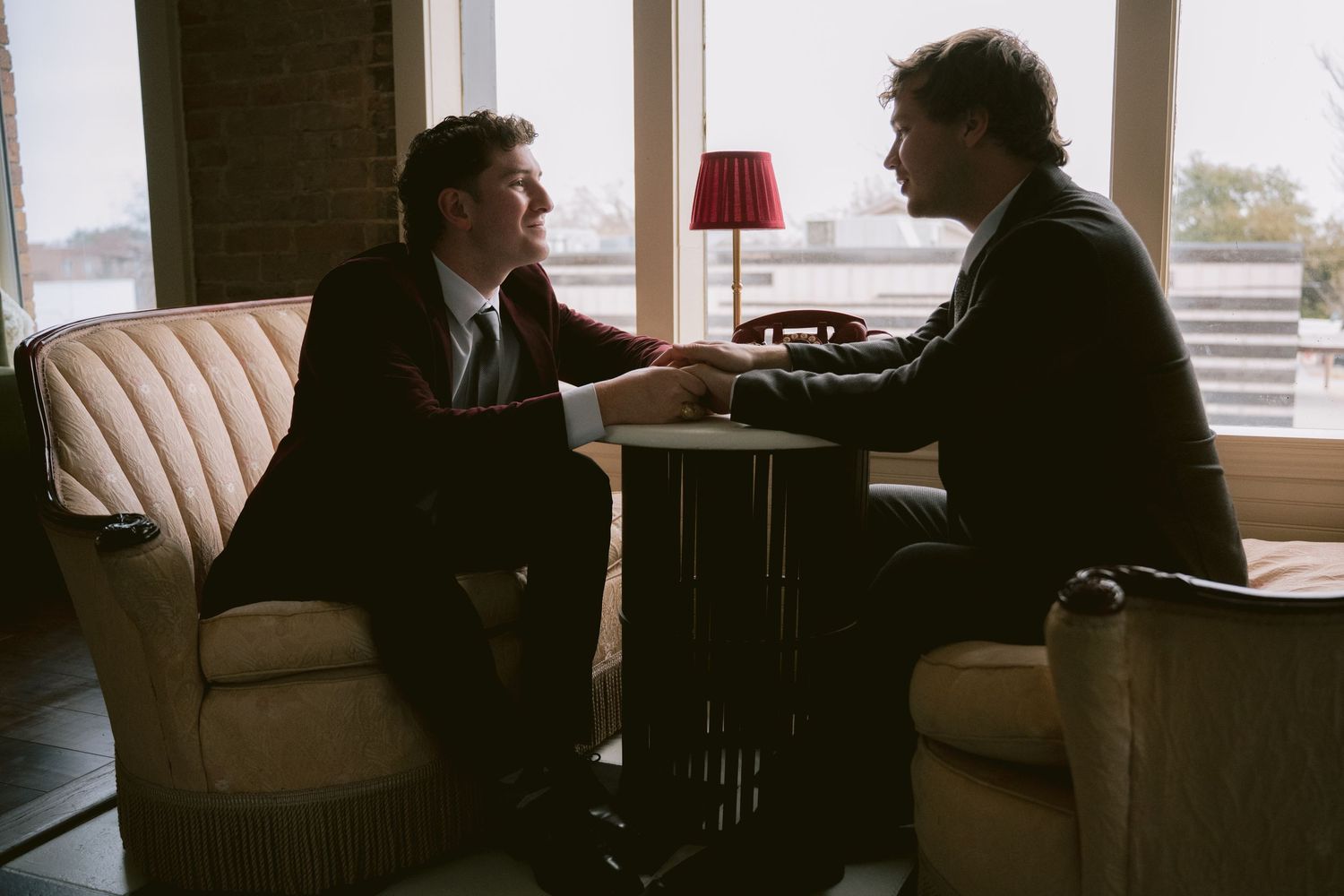 Two grooms chatting over a table and holding hands