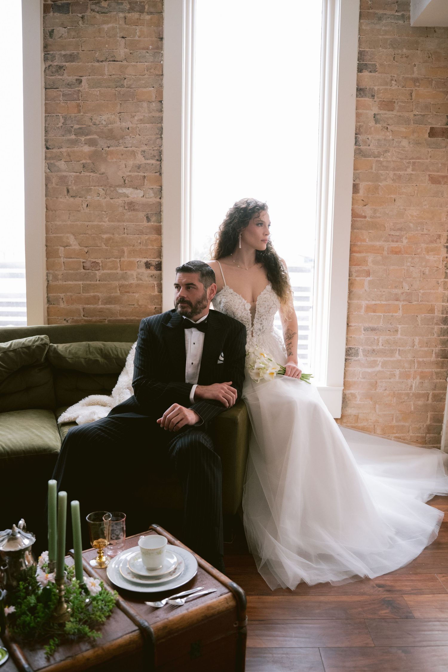 A bride and groom posing in front of a bright window