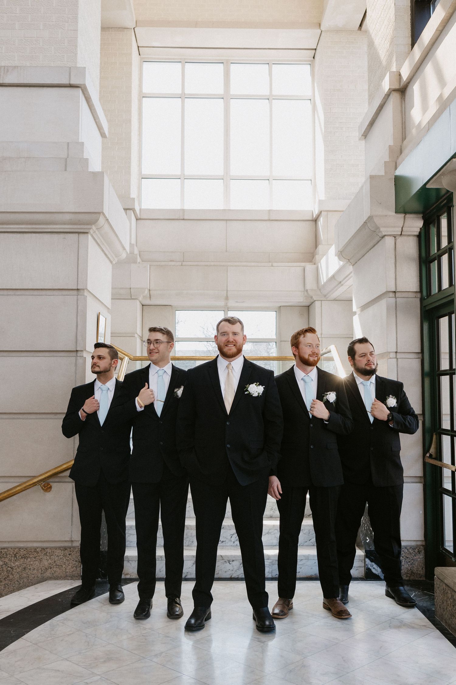 Groom and groomsmen at the Leo Ballroom entrance with grand marble steps.