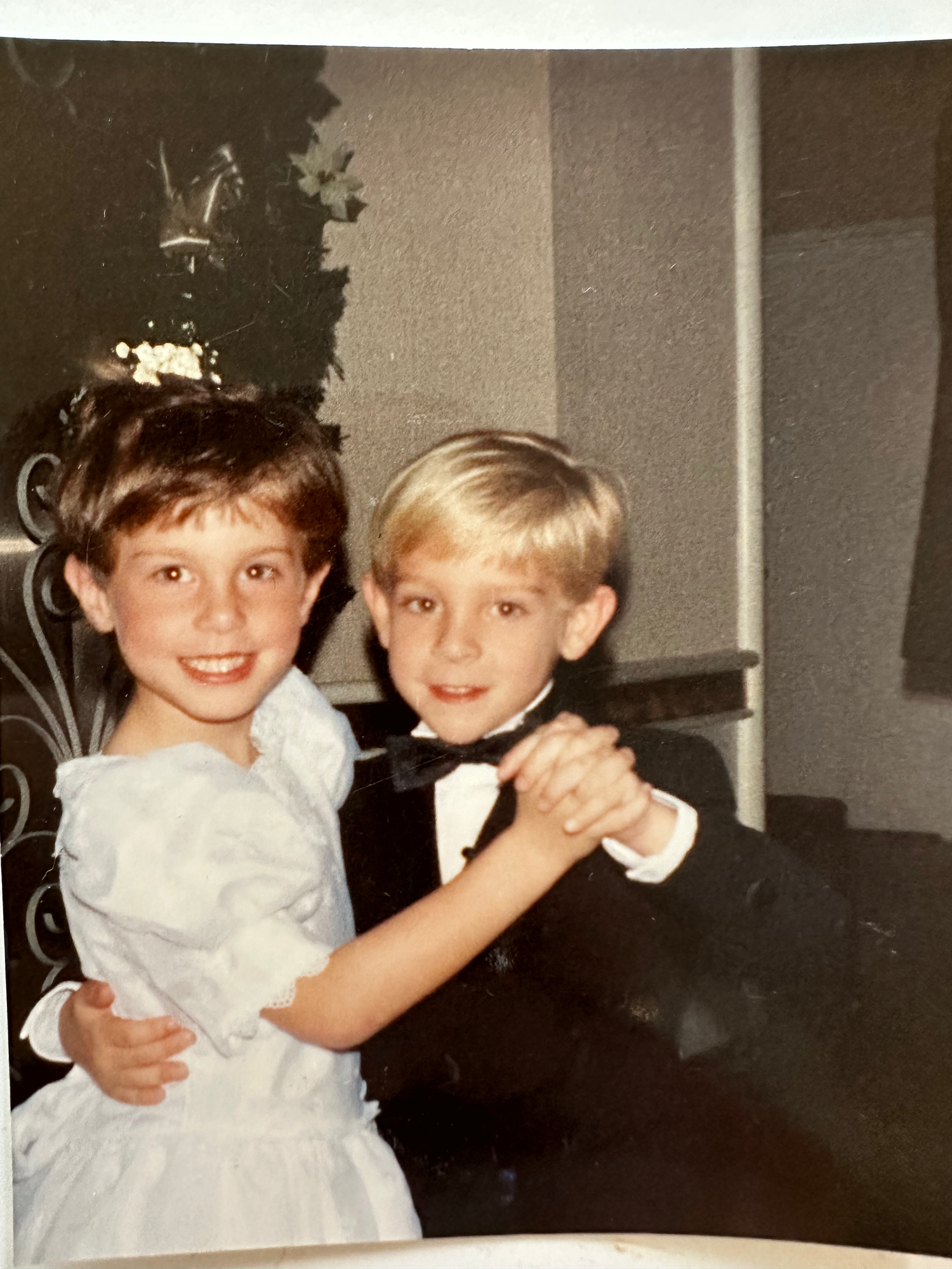 A series of vintage photographs showing two children sitting side by side at what appears to be a dining table.