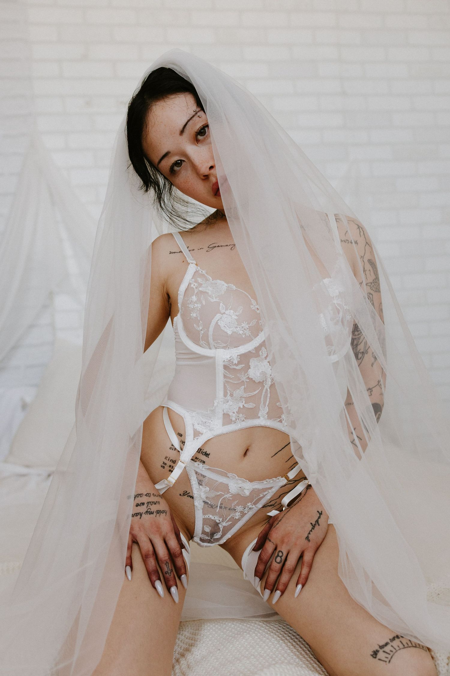 Bridal Boudoir portrait photographer in Plattsmouth Nebraska in an intimate private studio. woman is posing in white lingerie in veil