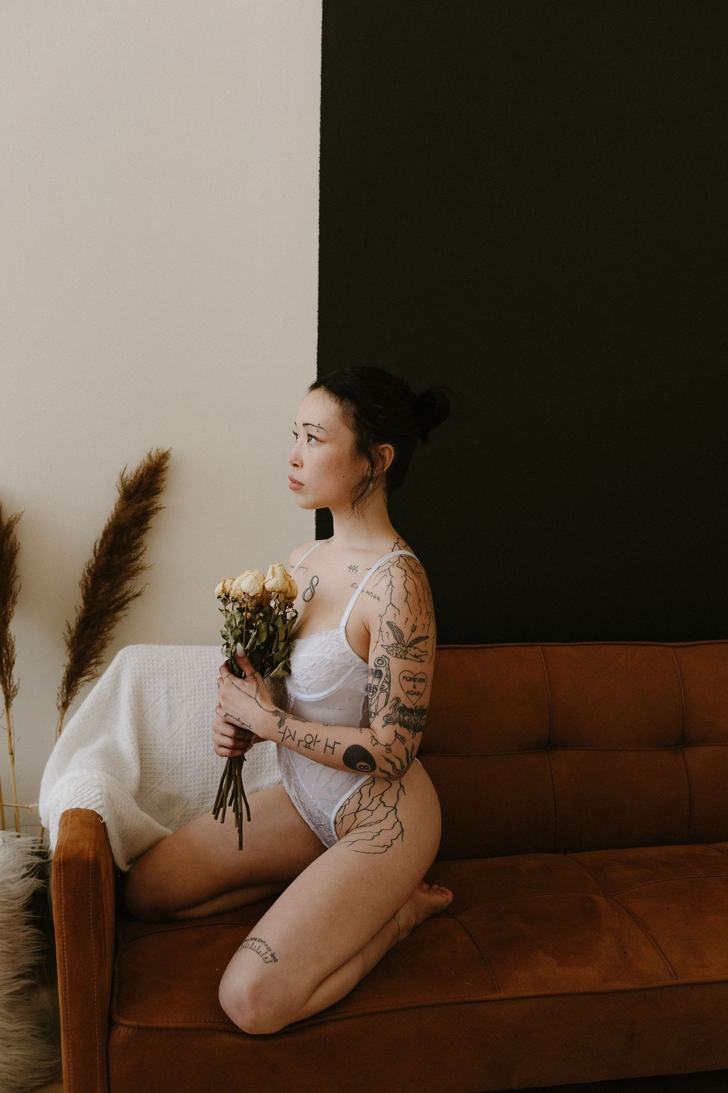 Woman posing with flowers in white lingerie in a private studio in Plattsmouth Nebraska for a bridal boudoir session