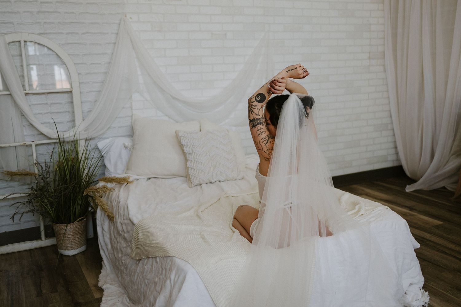 Woman posing her veil in white lingerie on a bed in a private studio in Plattsmouth Nebraska for a bridal boudoir session