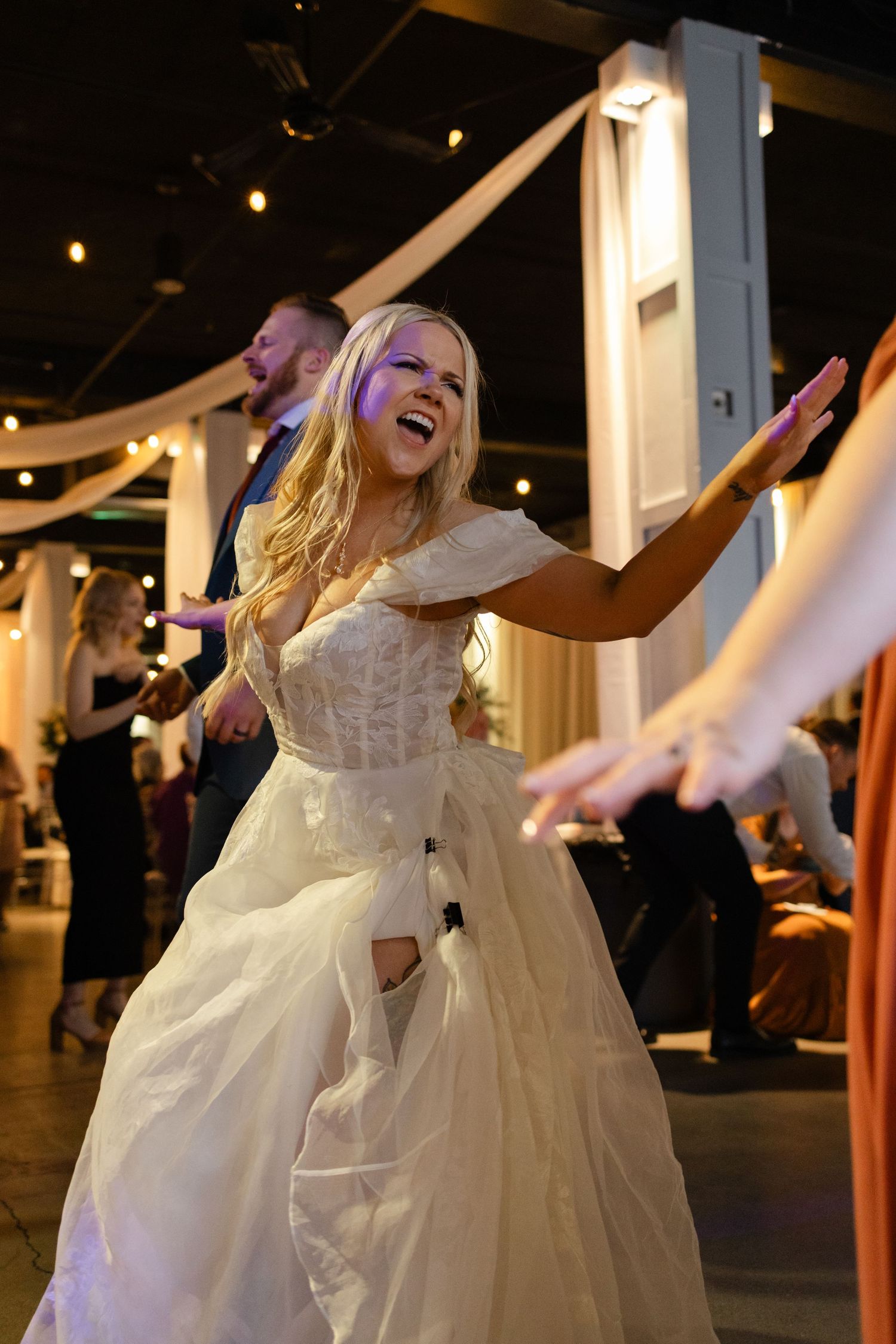 A bride in a flowing white dress dances joyfully on the dance floor at a wedding reception at Diamond Room, Omaha Nebraska