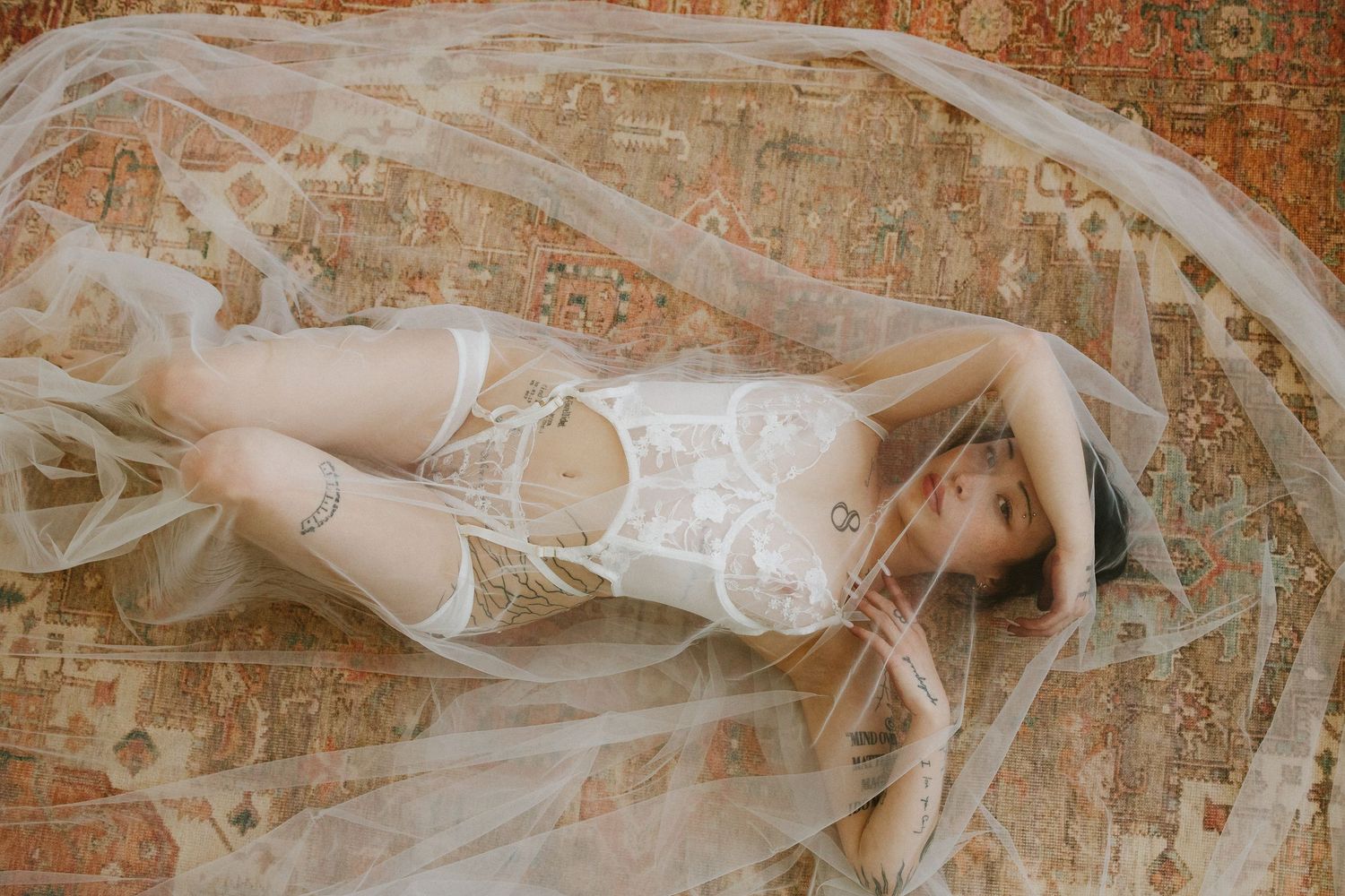 Plattsmouth Nebraska bridal boudoir photographer bride is posing on a rug with a veil draped over her.
