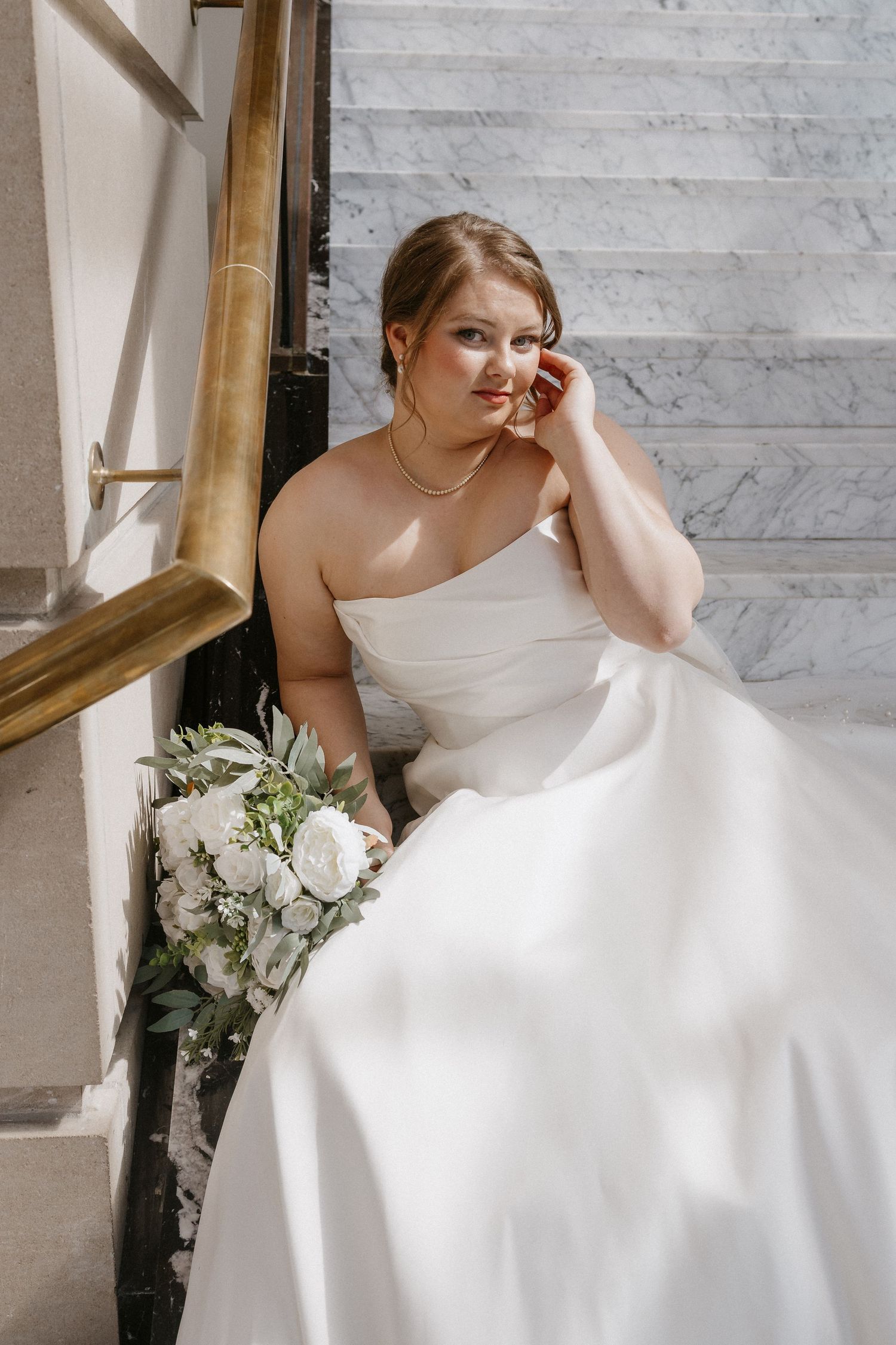 bride sitting on marble steps at the Leo Ballroom Omaha wedding portraits