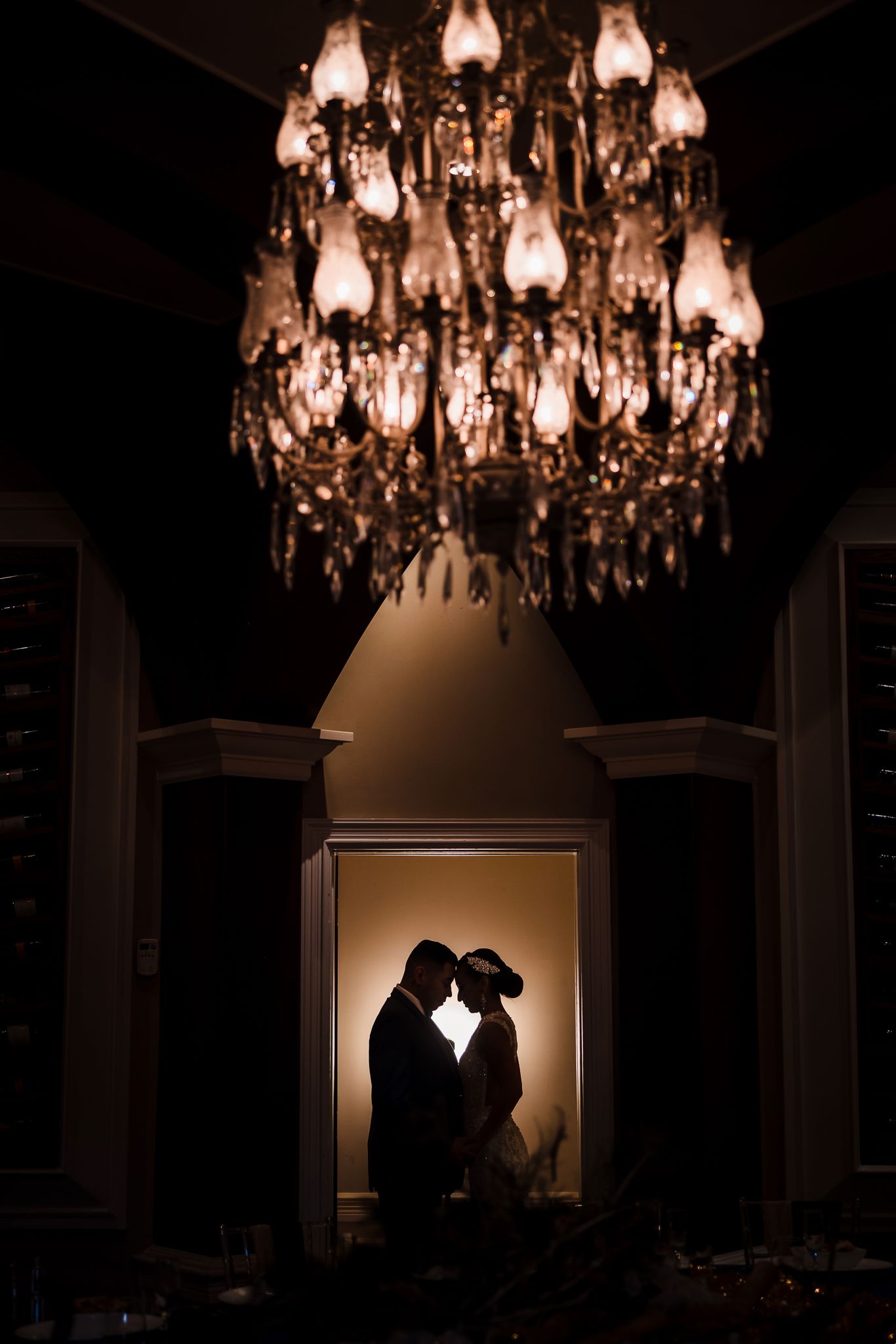 Bride and groom kissing under chandelier