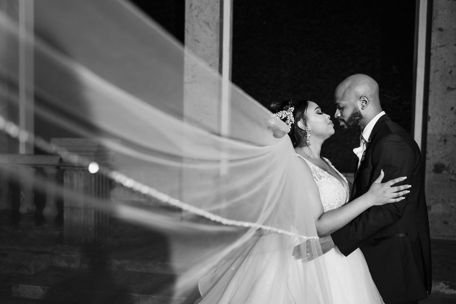 Couple kissing at the blue-lit Waterwall, Bell Tower on 34th at night