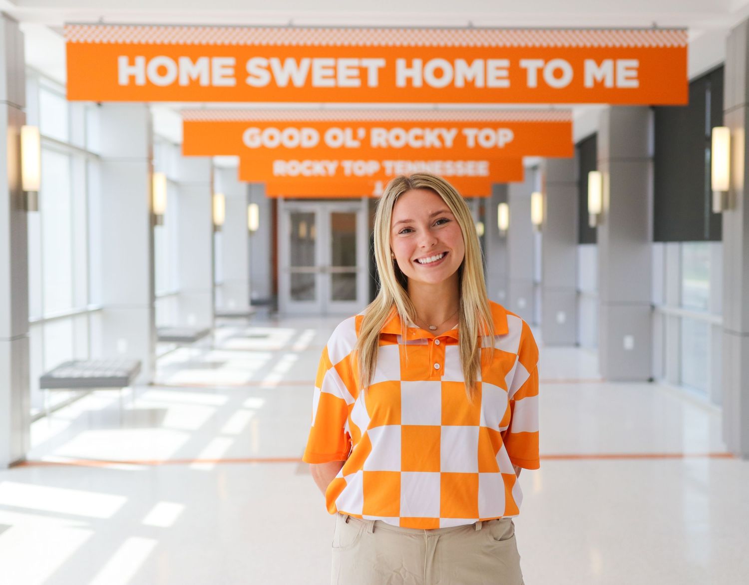 Bright orange and white checkered banners hang in modern white hallway with large windows.