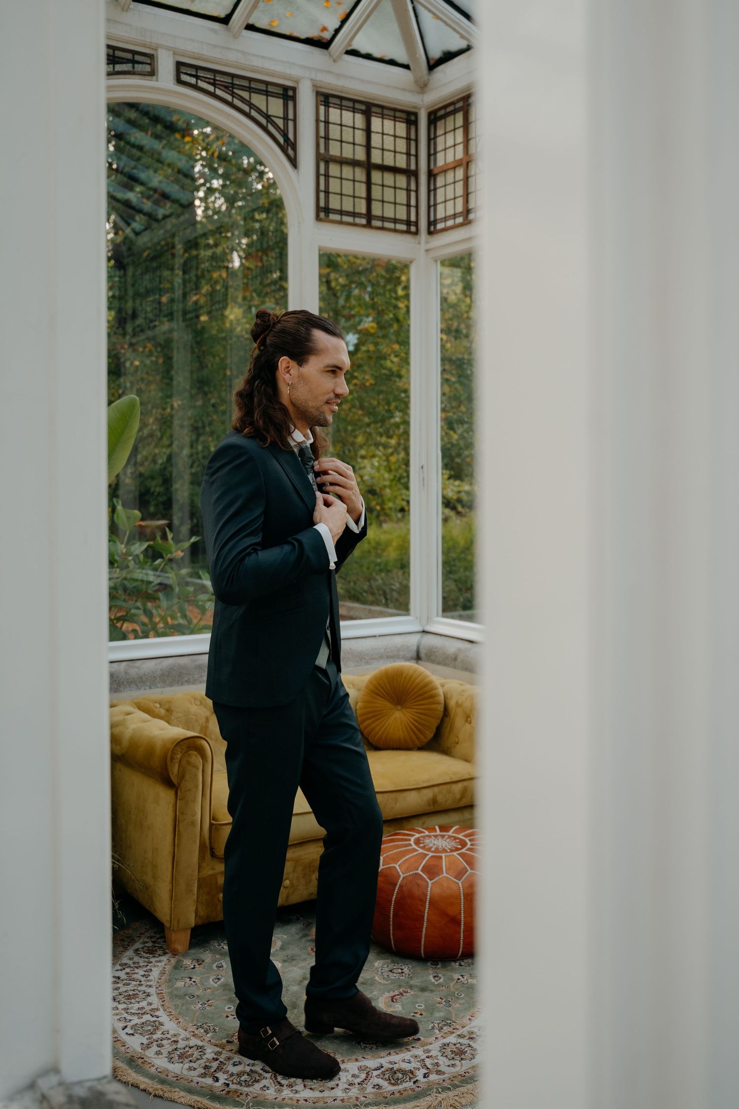 A couple shares an intimate moment in a sunlit room with white columns and yellow furniture.