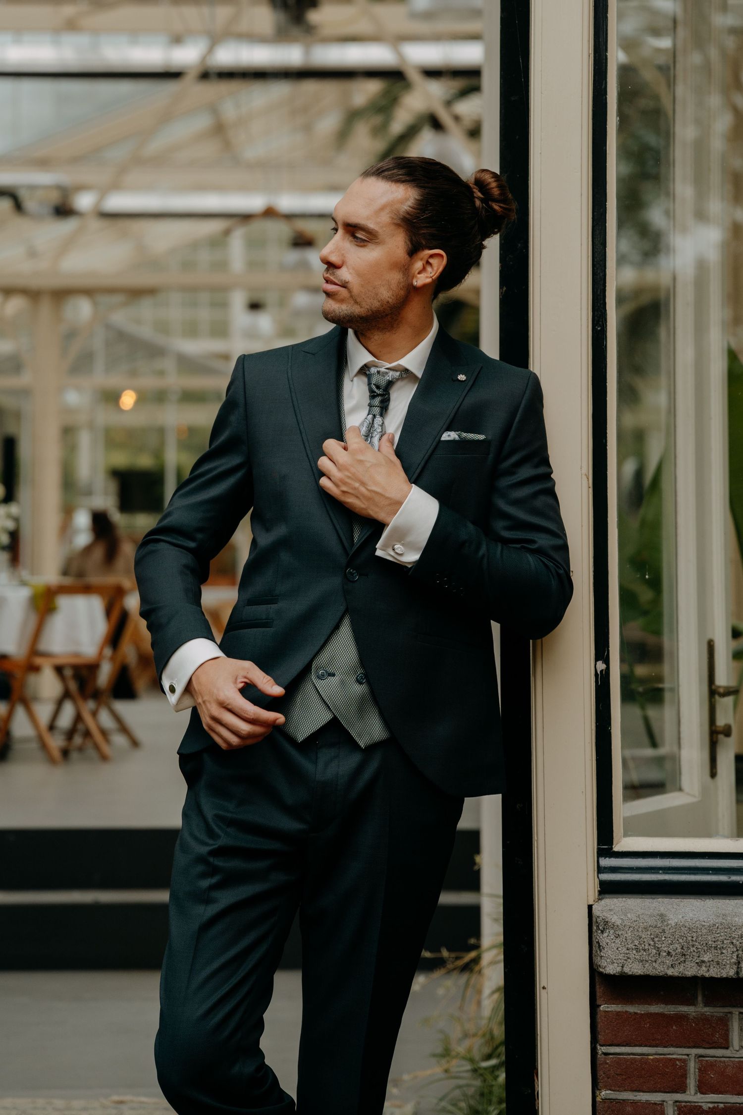 Groom in classic black tuxedo adjusting his tie before the ceremony.