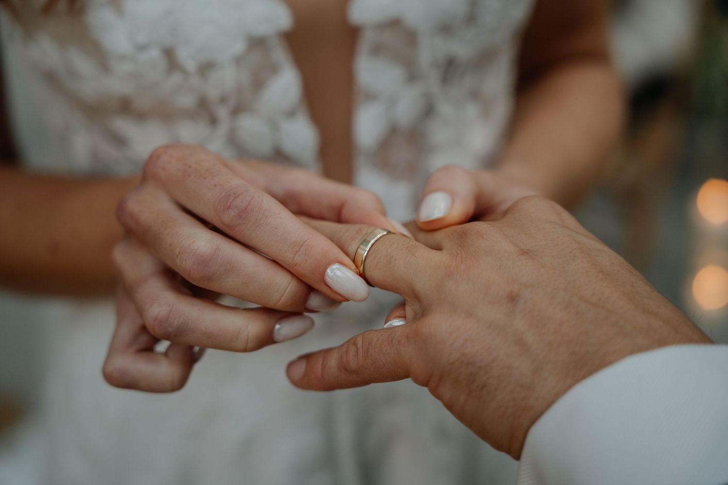 Detail shot of hands exchanging rings during a wedding ceremony.