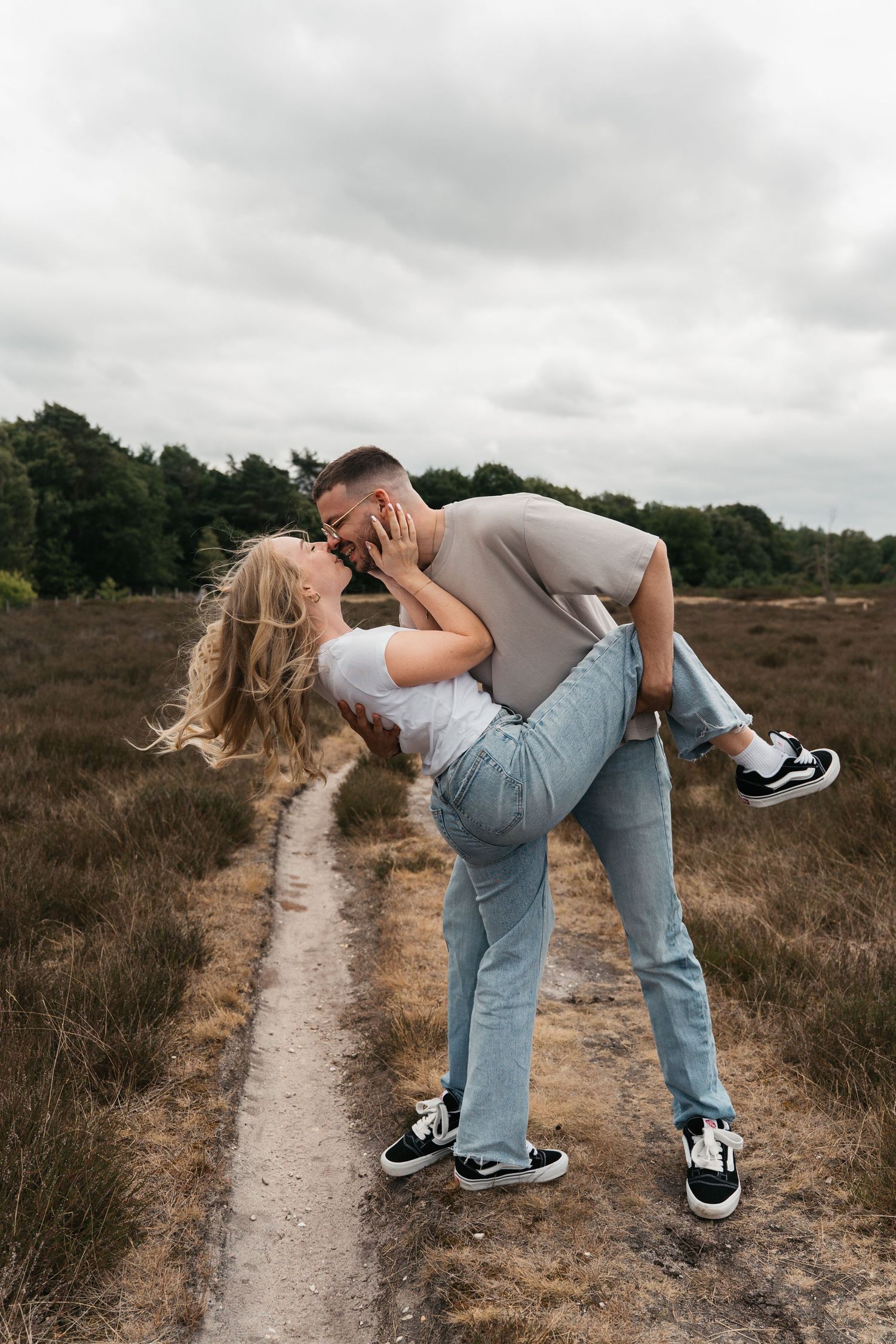 Een verliefd stel op de paarse heide in Laren tijdens een frisse lentedag.