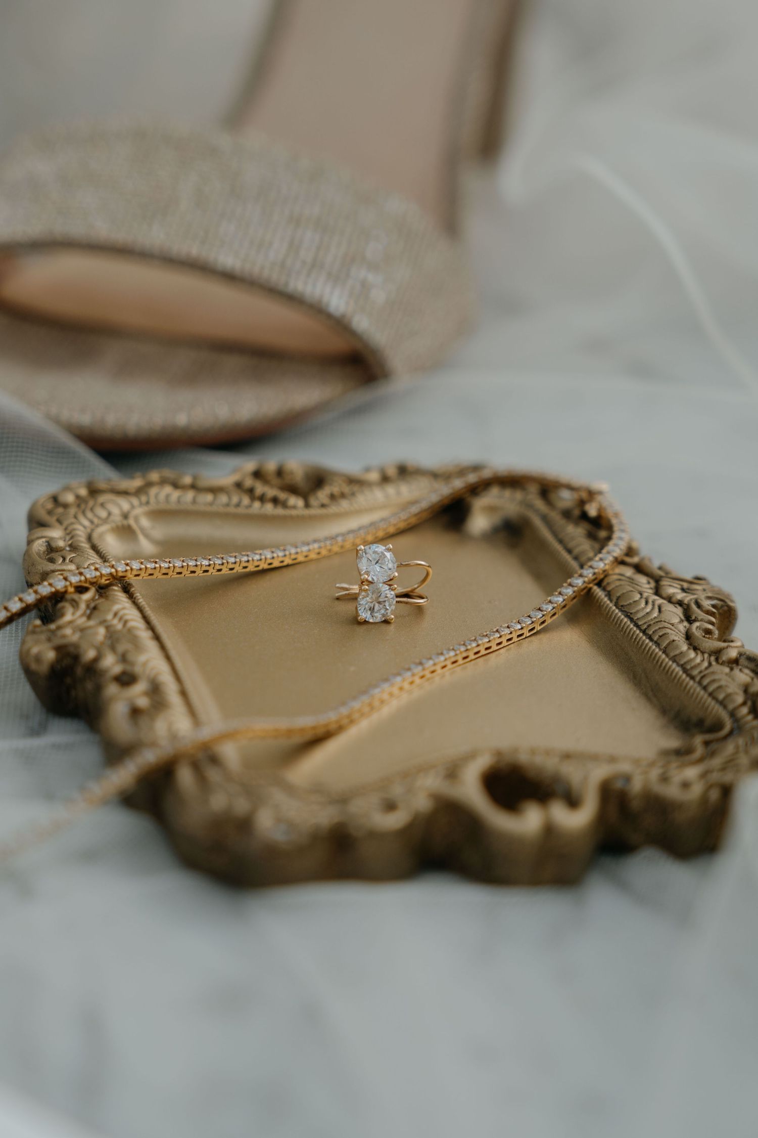 Close-up view of an engagement ring with a small diamond solitaire on a beige suede or velvet surface.
