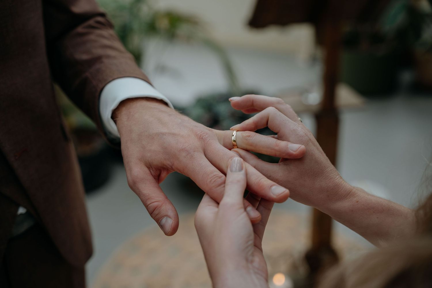 Close-up shot of hands exchanging rings during an intimate wedding ceremony outdoors.