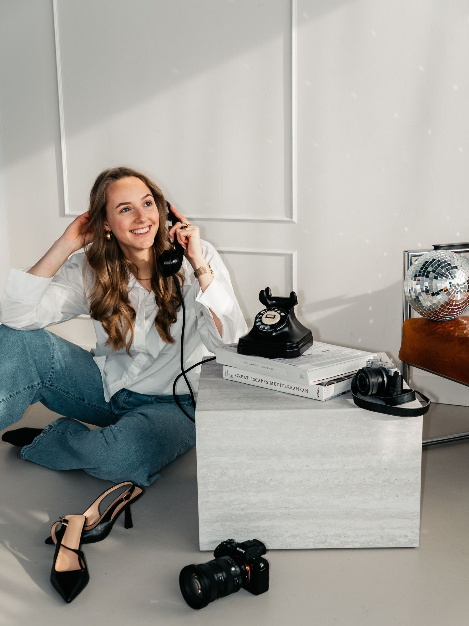 Lifestyle photo with vintage telephone, camera and heels in modern minimalist setting.
