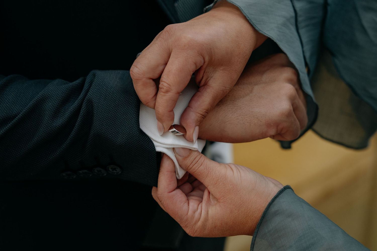 Close-up shots of hands exchanging rings during an intimate wedding ceremony.