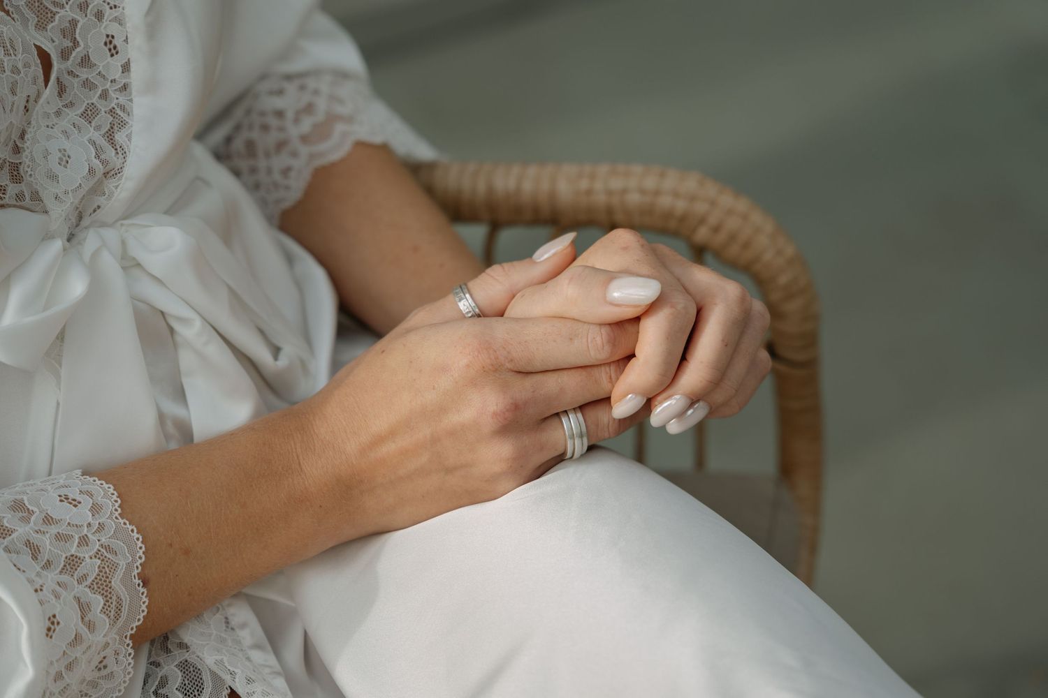 Close-up of hands with wedding rings and delicate lace details.