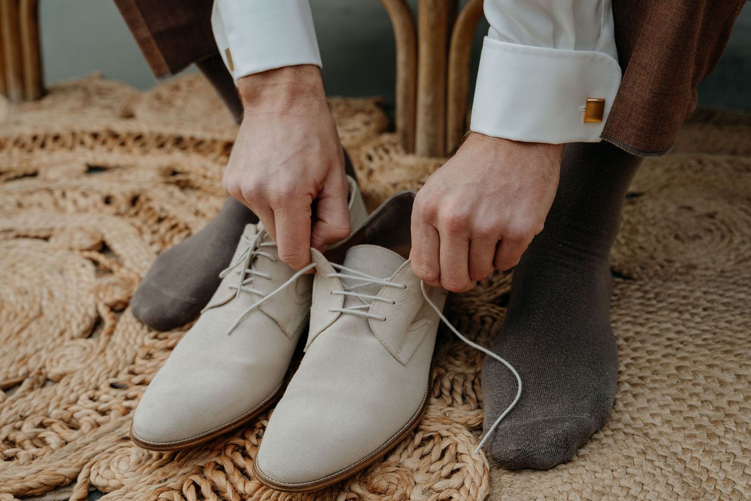 A row of neutral-colored suede and leather dress shoes displayed on a beige carpet.
