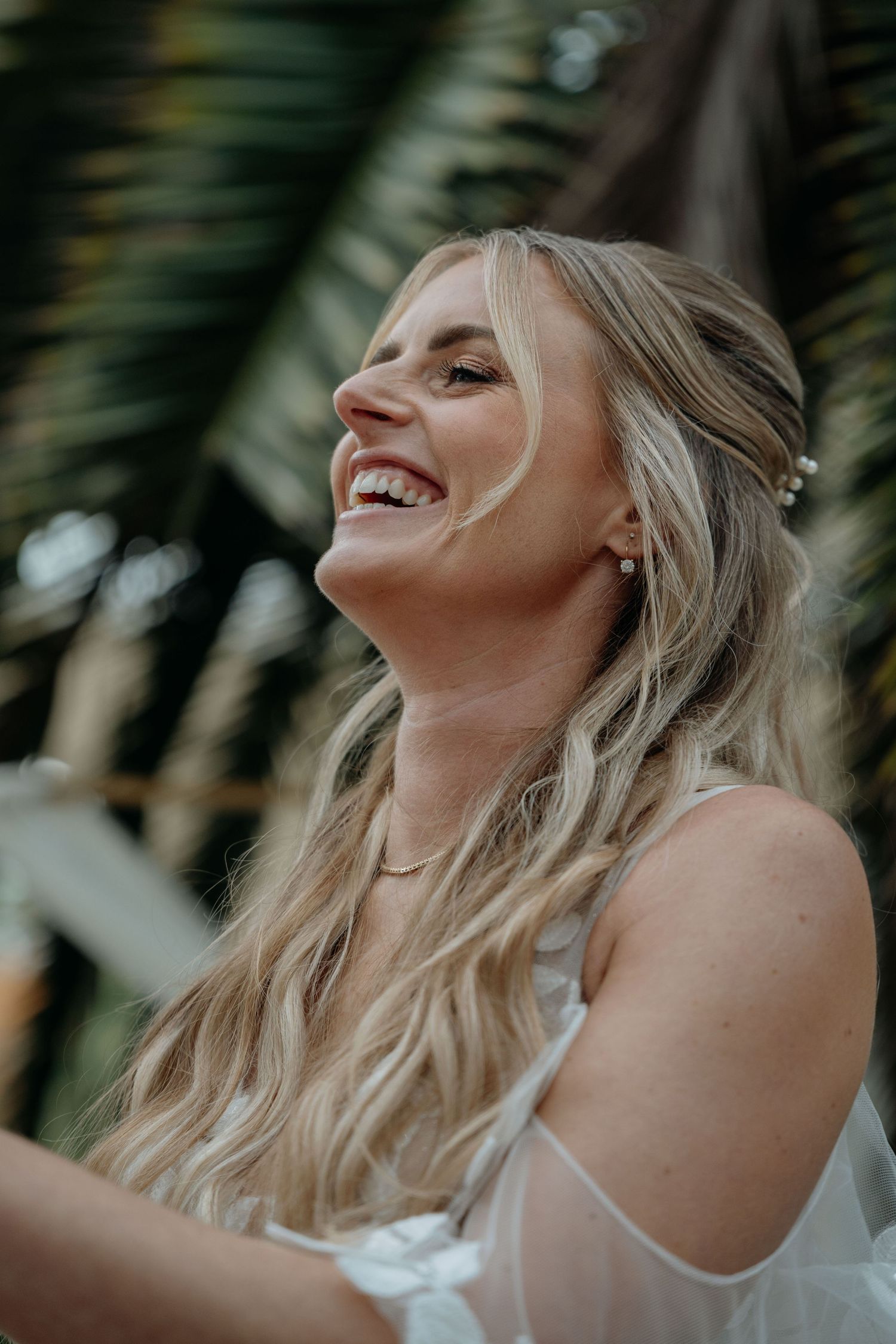 Joyful laughter captured in natural light with palm fronds in background creating tropical ambiance.