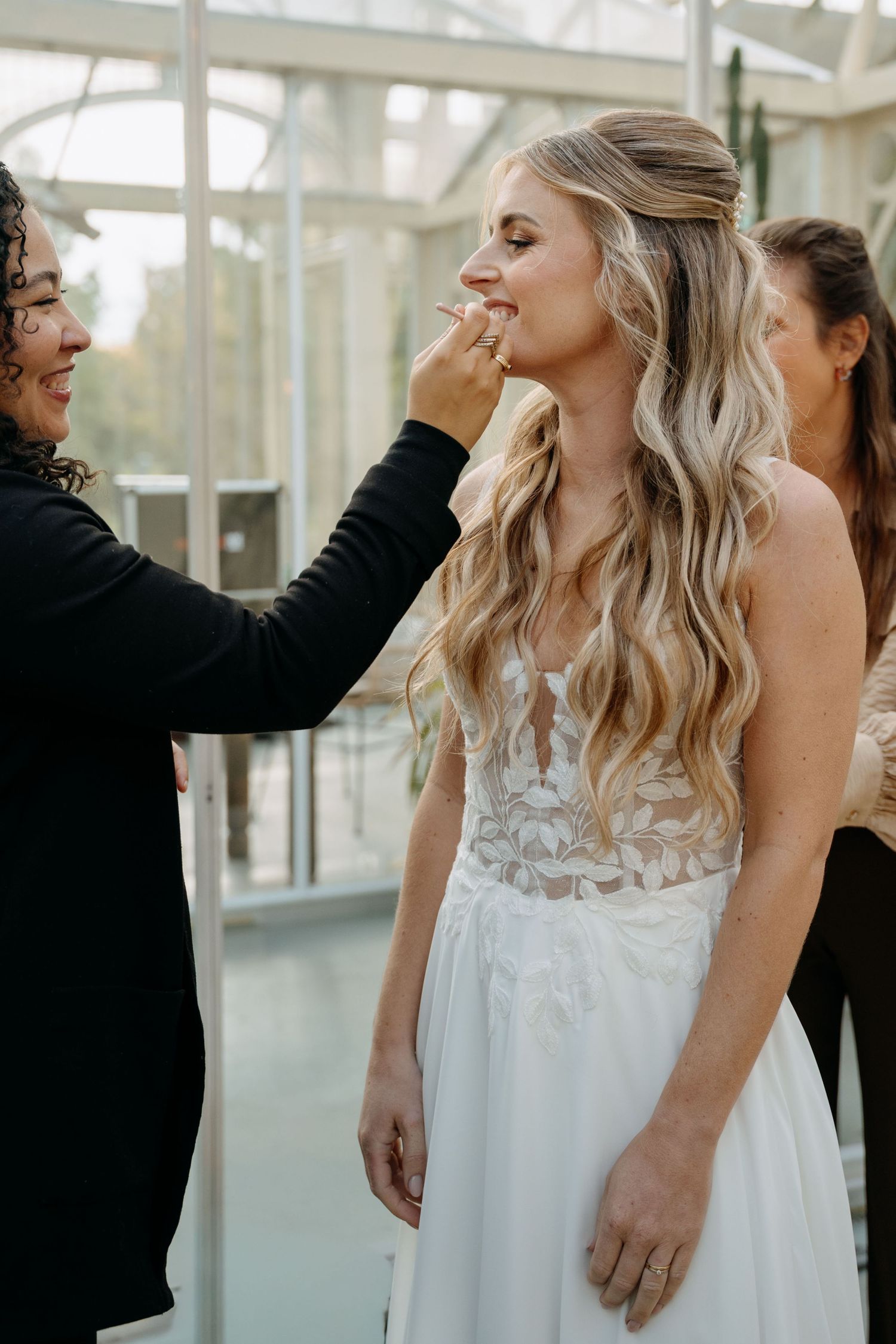 Joyful wedding couple sharing laughter in a bright sunlit conservatory space.