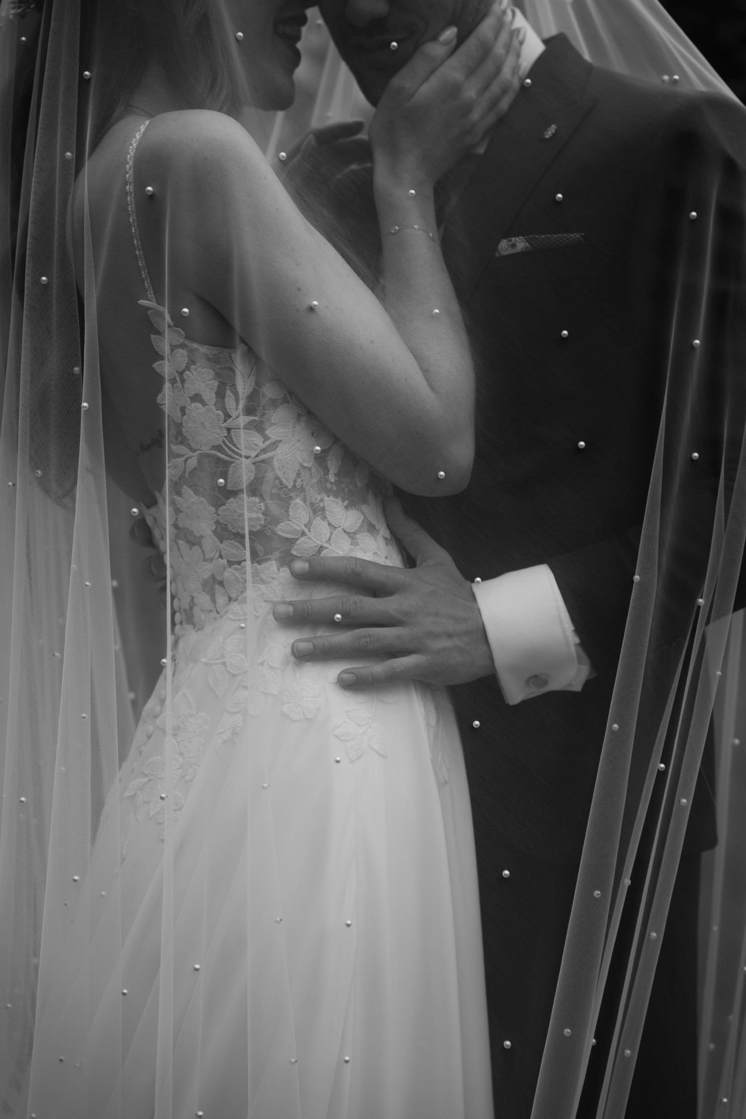 Close-up details of a wedding dress with delicate beading and veil in black and white.