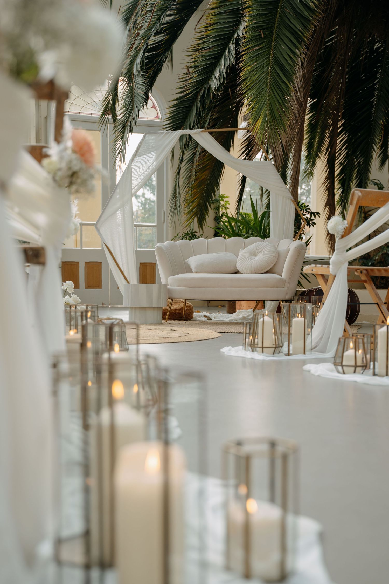 Modern white interior space with palm plants and hanging lanterns creating a tropical luxury atmosphere.