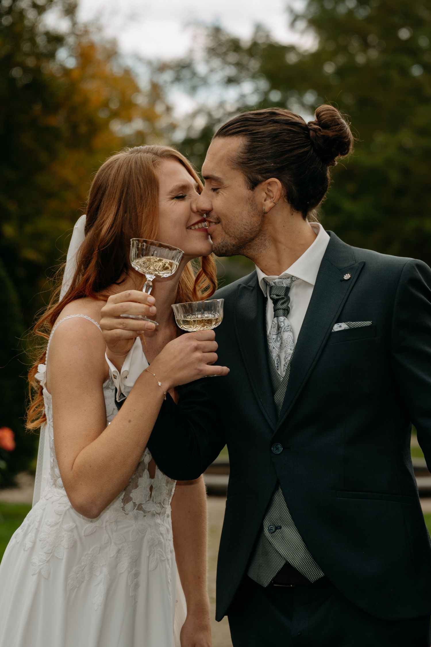 Newlyweds share champagne and intimate moments in an outdoor autumn setting.