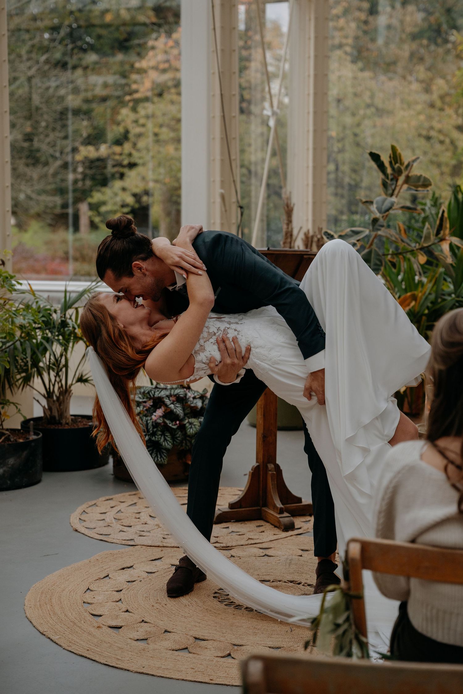 Dramatic dip kiss pose by newlyweds in indoor venue setting.