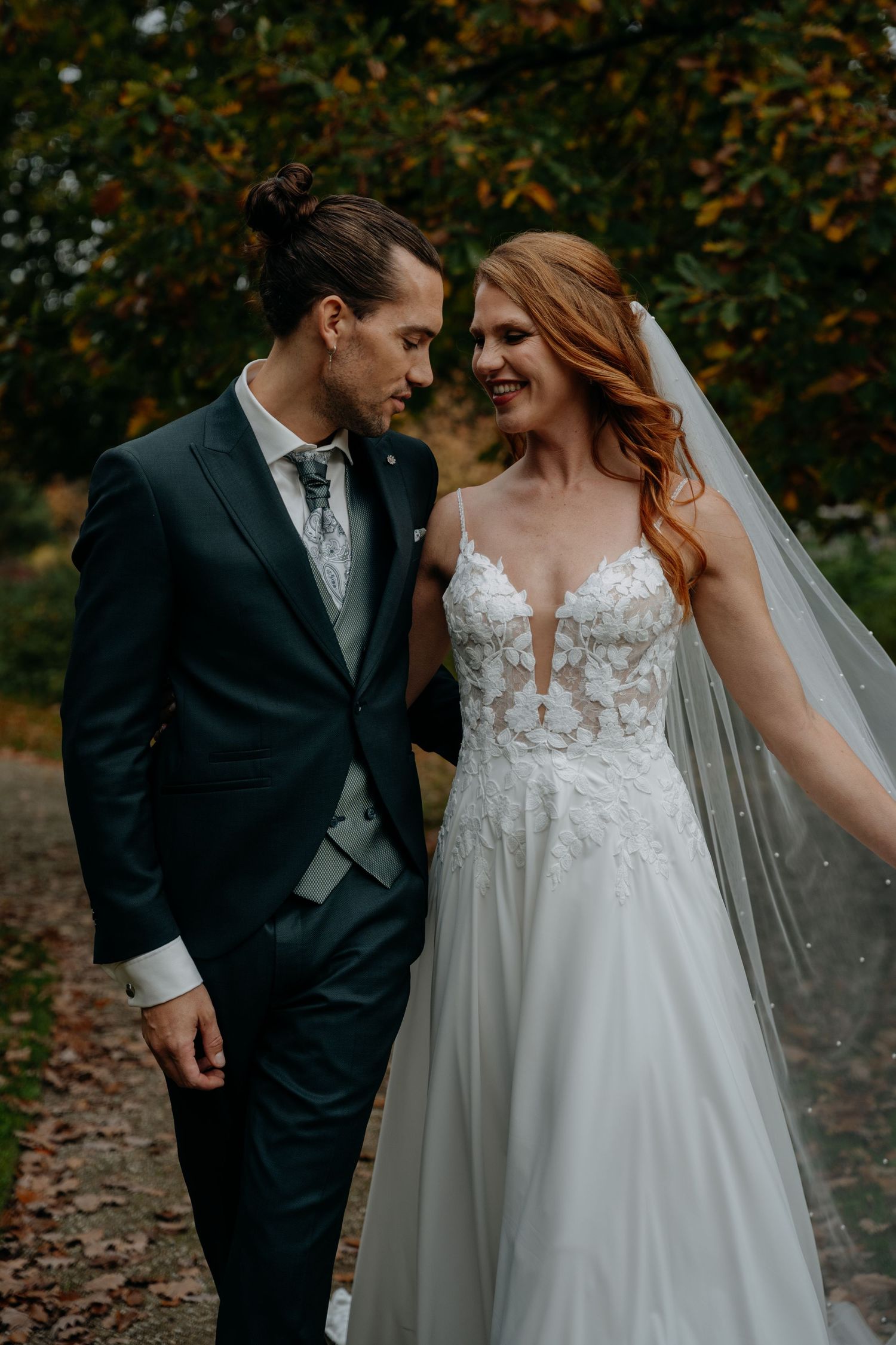 Romantic autumn wedding portrait with falling leaves in the background.