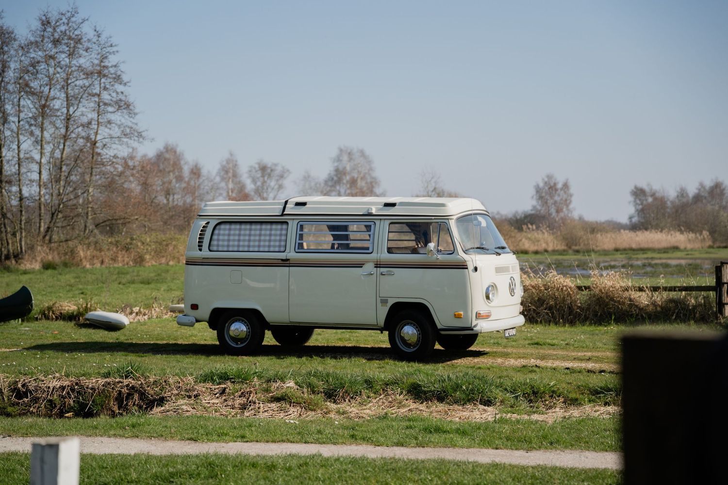 Vintage VW Type 2 camper van parked in a green field on a sunny day.