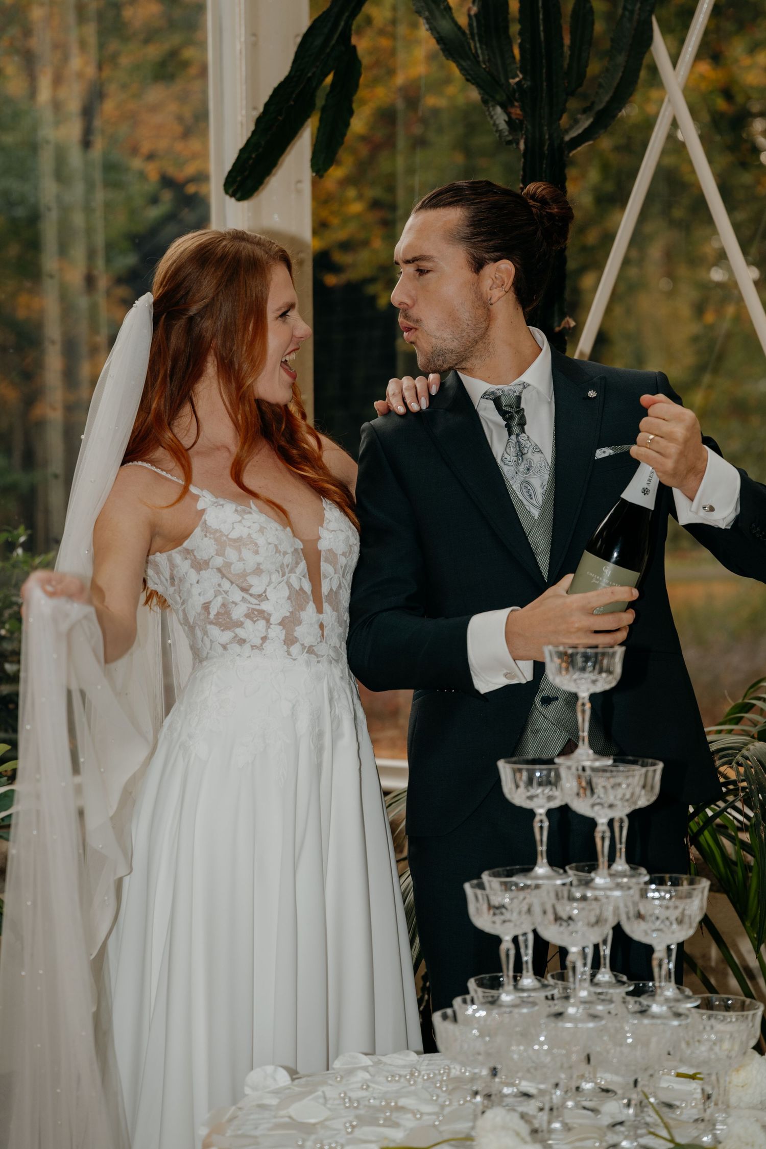 Wedding couple near champagne tower during reception celebration.