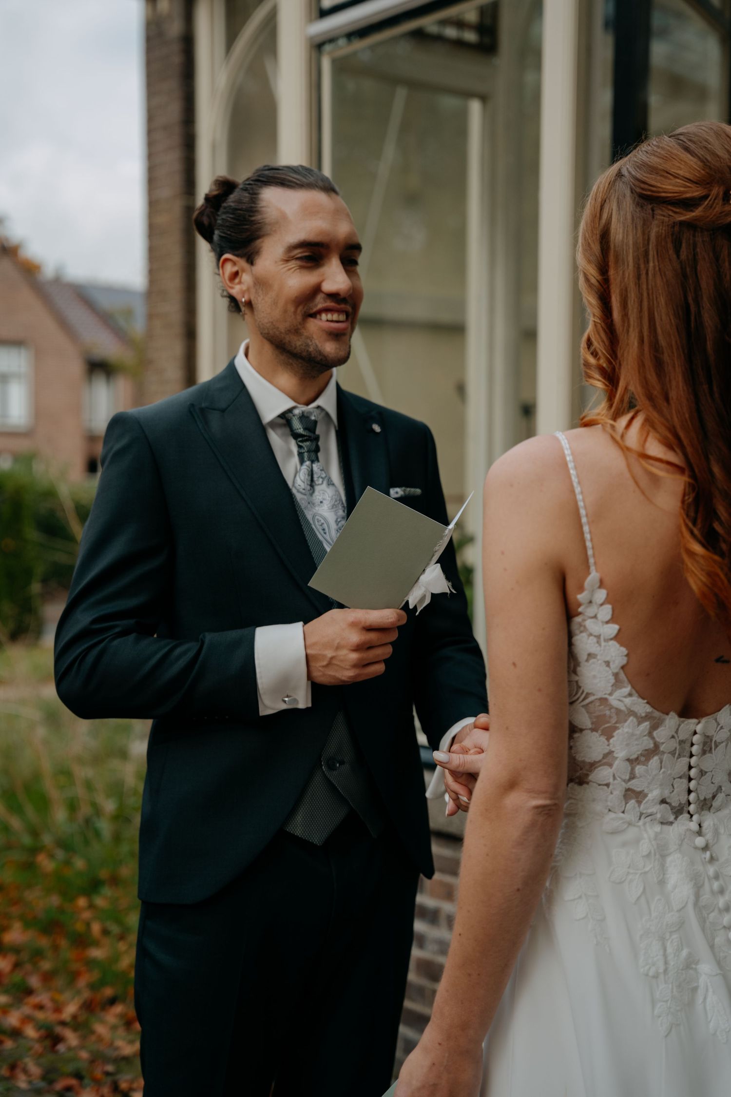 Couple sharing intimate moments while reading wedding vows outdoors.