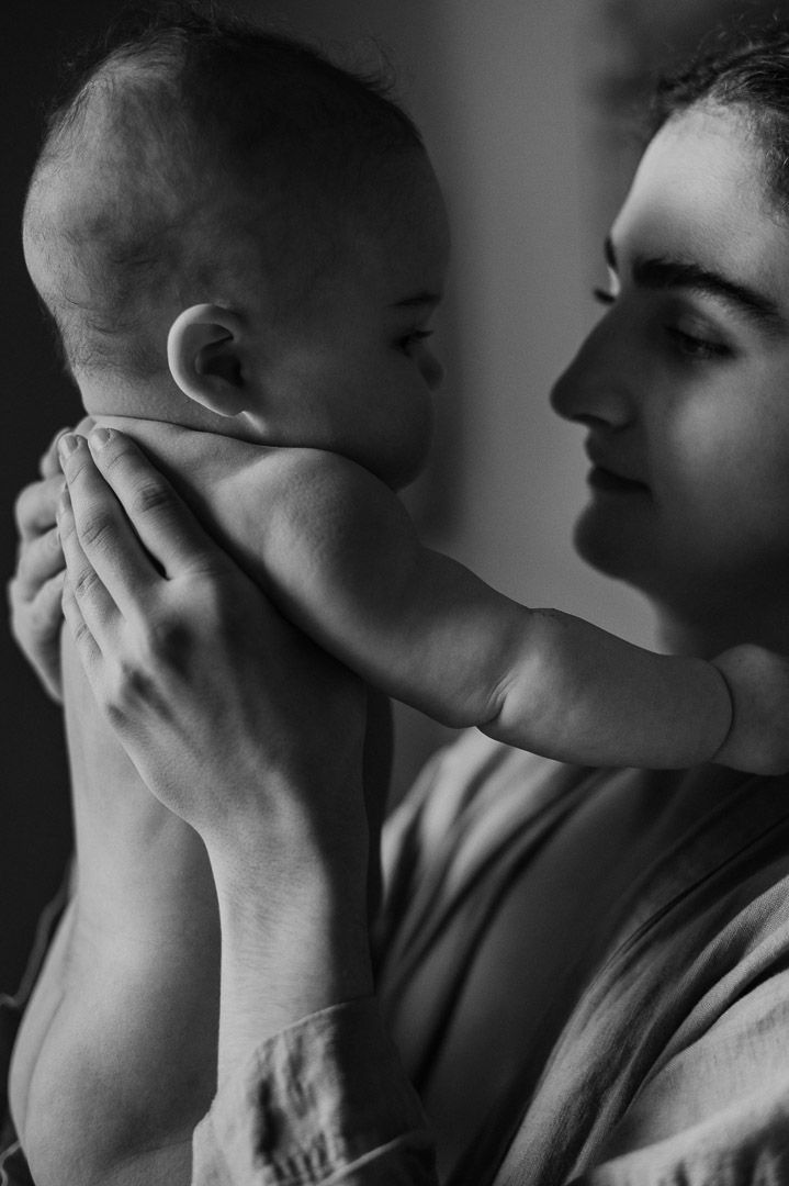Mutter hält Baby vor ihr Gesicht und lächelt liebevoll