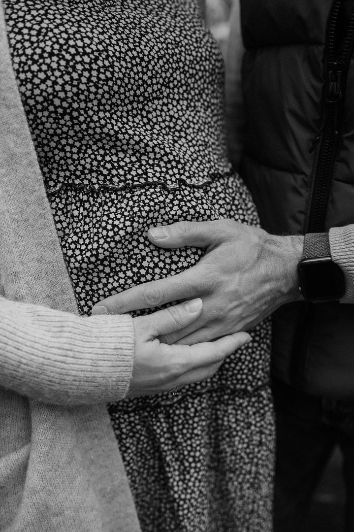 Mann und Frau halten Hände auf Babybauch
