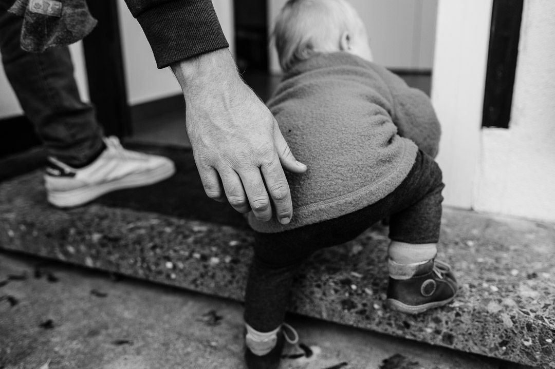 große Hand hilft Baby beim Stufensteigen