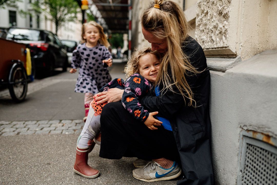 zwei Mädchen laufen in die Arme ihrer sitzenden Mutter