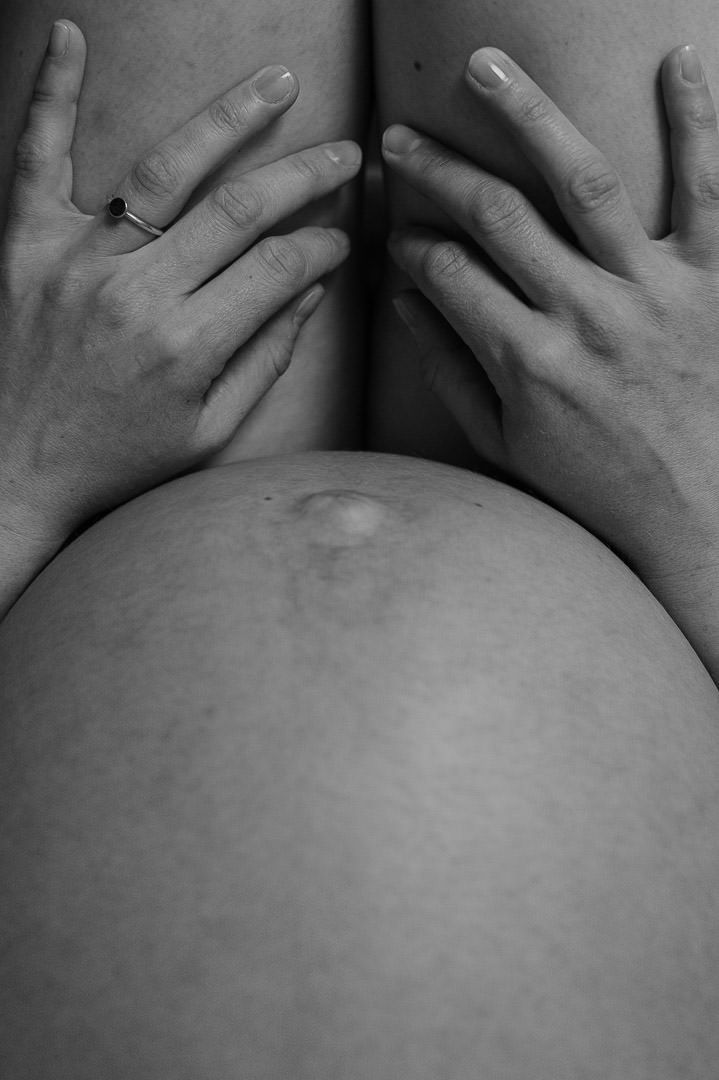 Detailbild eines Babybauchs und Hände