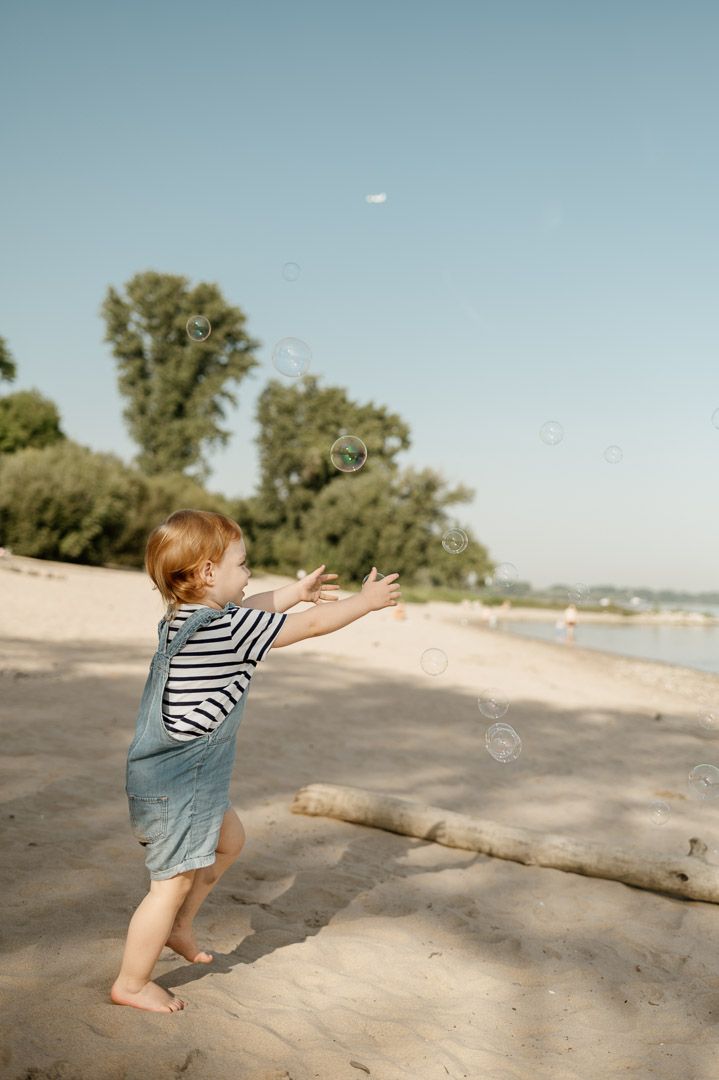 ein Kleinkind spielt Seifenblasen am Strand