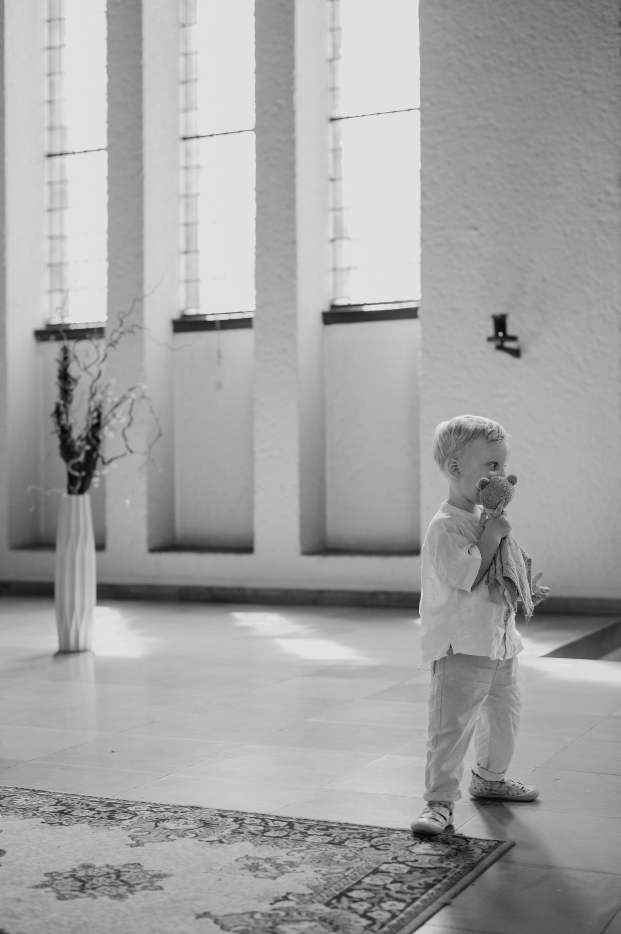 Kind spielt mit Teddy in einer Kirche bei Taufreportage