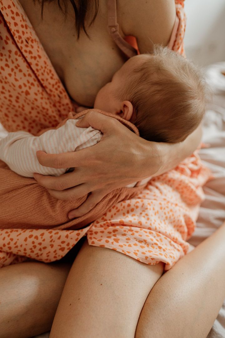Frau mit Kleid stillt Baby