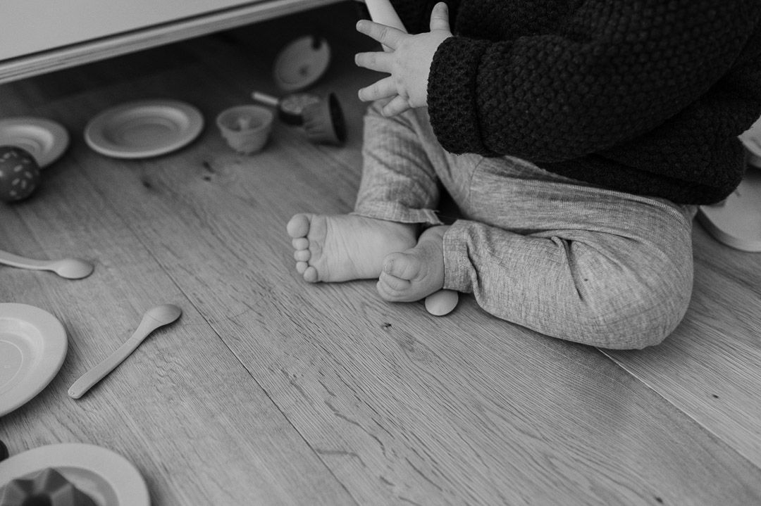Füsse eines sitzenden Kindes im Chaos einer Spielküche