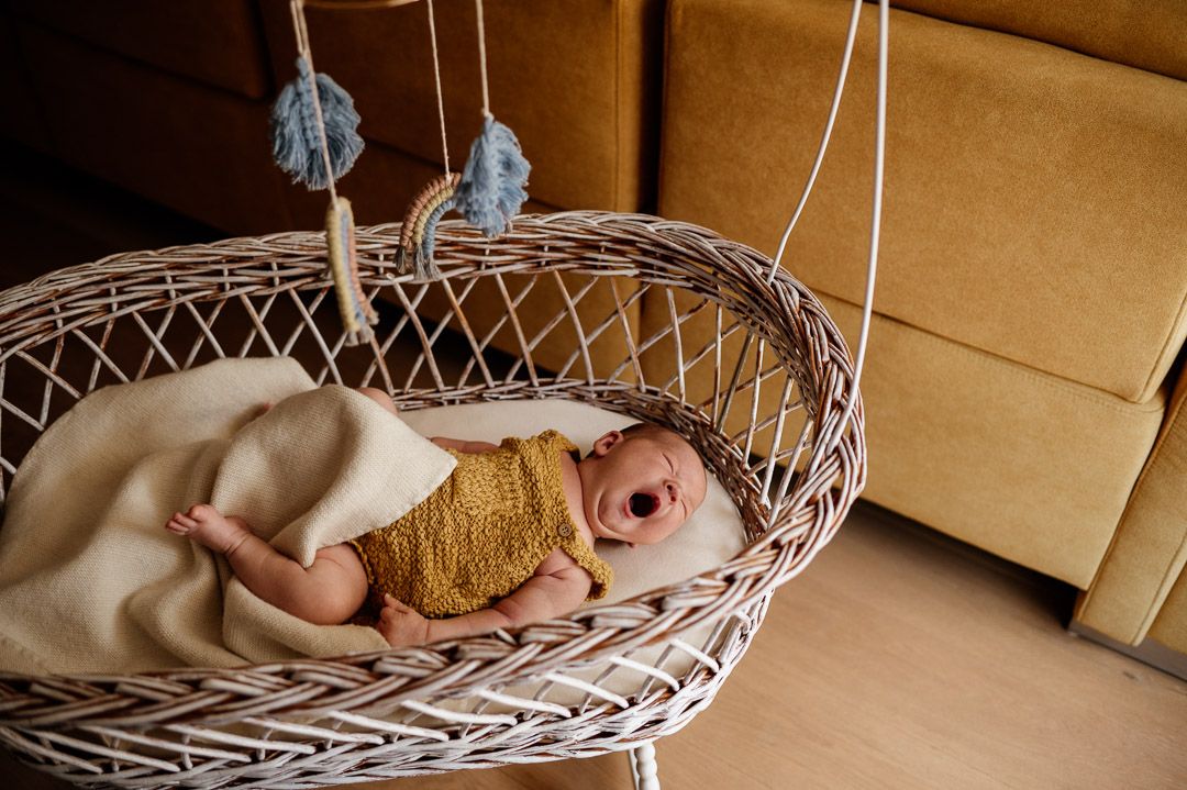 Baby gähnt genüßlich in seinem Stubenwagen vor gelber Couch