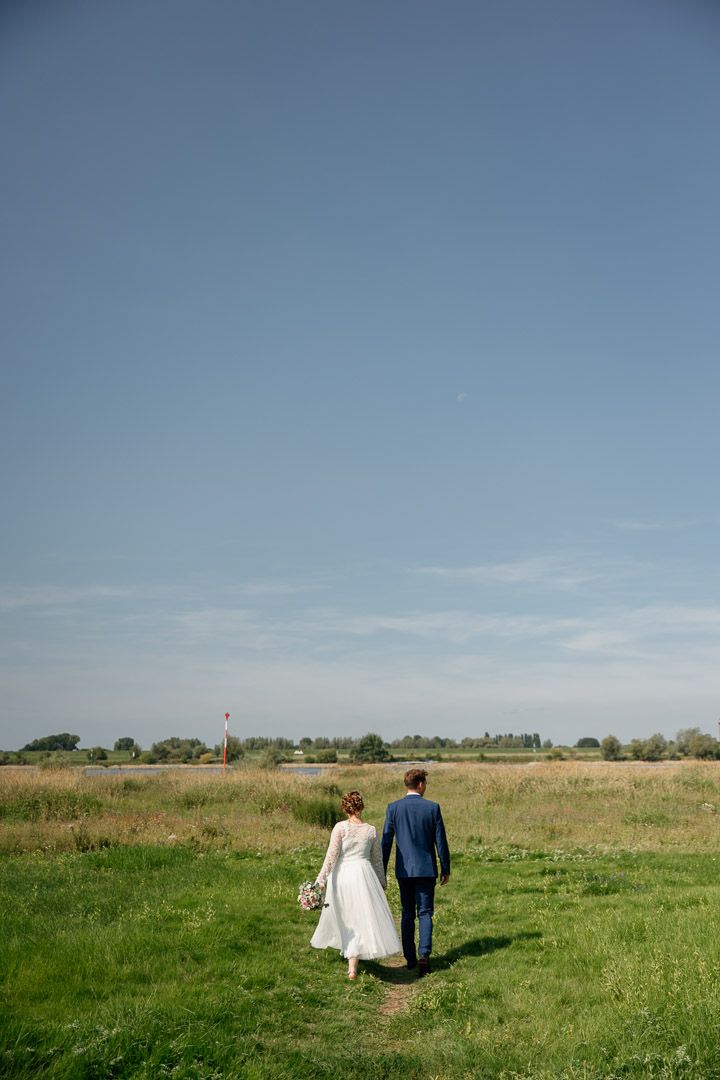 Hochzeitsfotografie eines Brautpaares von hinten am Rhein in Dinslaken
