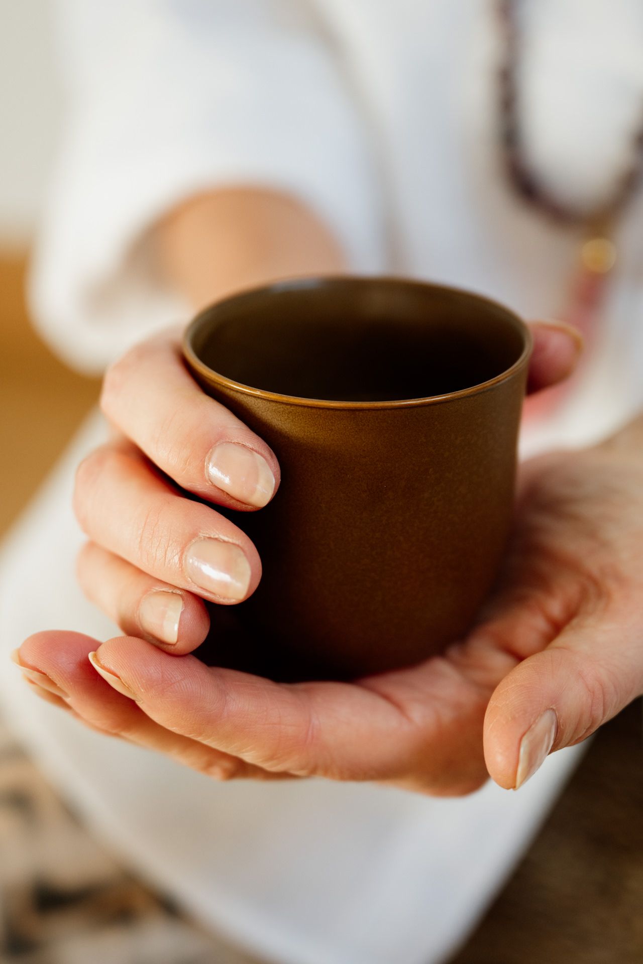 Hände halten eine dampfende Teetasse