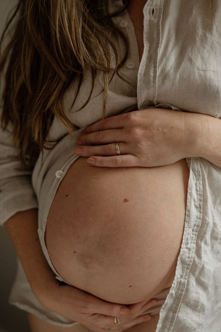 Babybauch schaut aus offenem Hemd