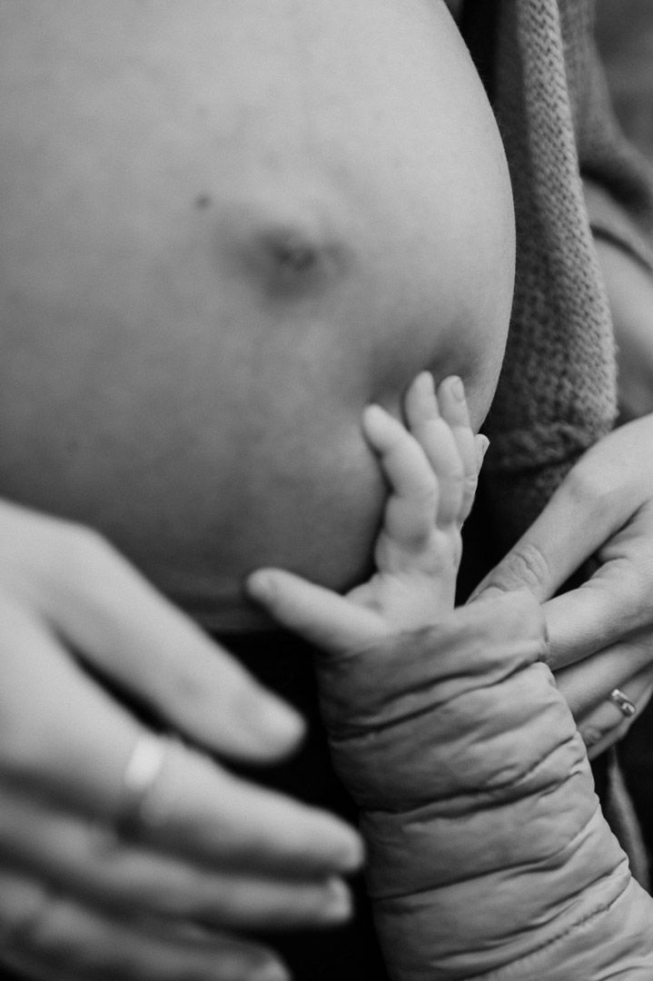 Kleinkind drückt in einen Babybauch mit Fingern