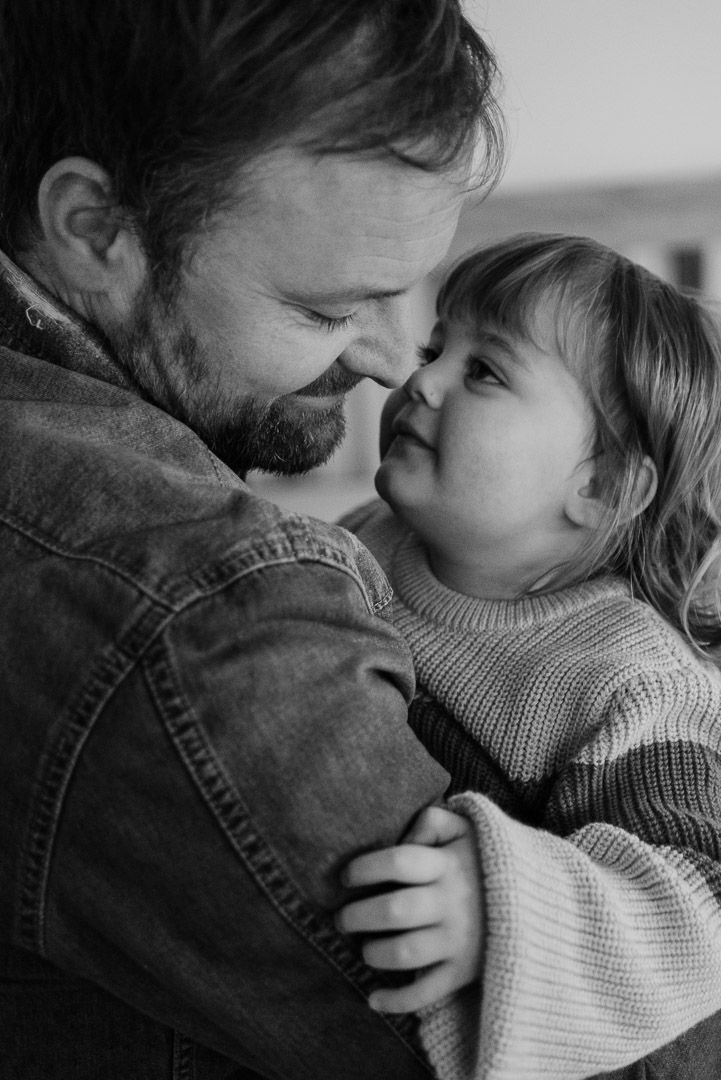 Kind mit liebevollem Blick in Papas Arm