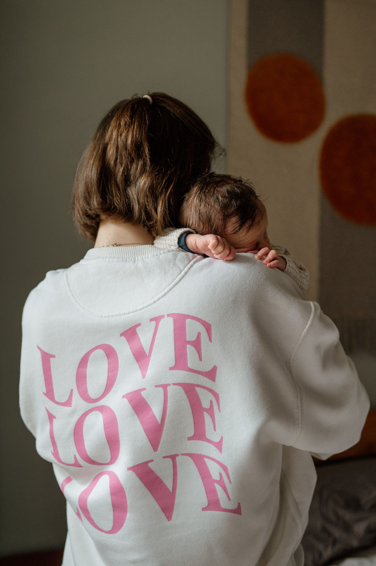 Rückenansicht einer Frau die ihr Baby auf dem Arm hält