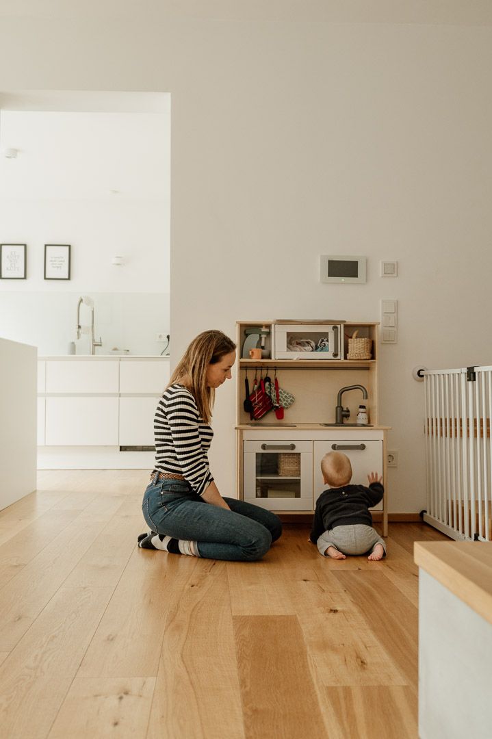 Mutter spielt mit Baby an Kinderküche während fotografischer Familiendokumentation